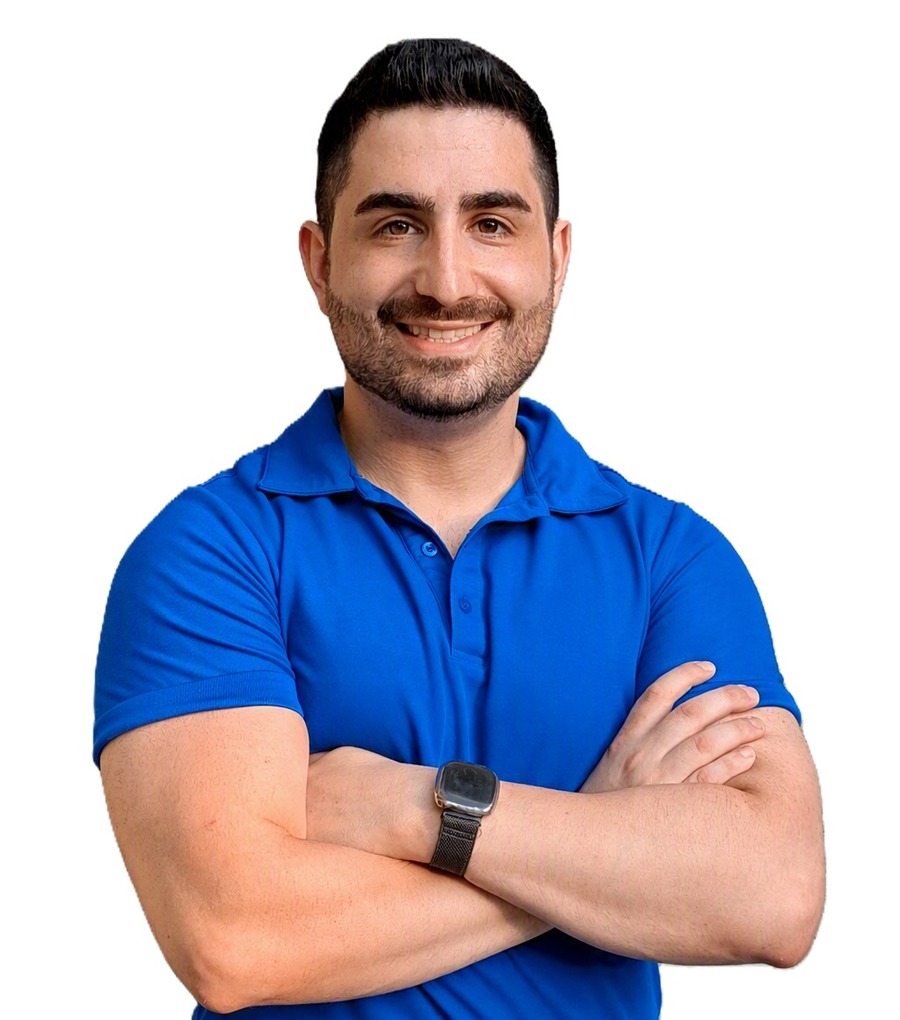 Adam Jordan standing with arms crossed, wearing a blue polo shirt